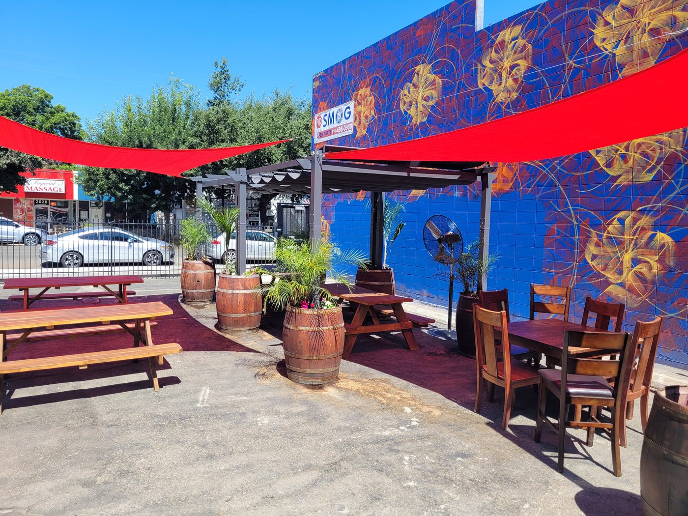 Outdoor seating area at Rendez-vous Winery with tables, barrels, and colorful wall art.